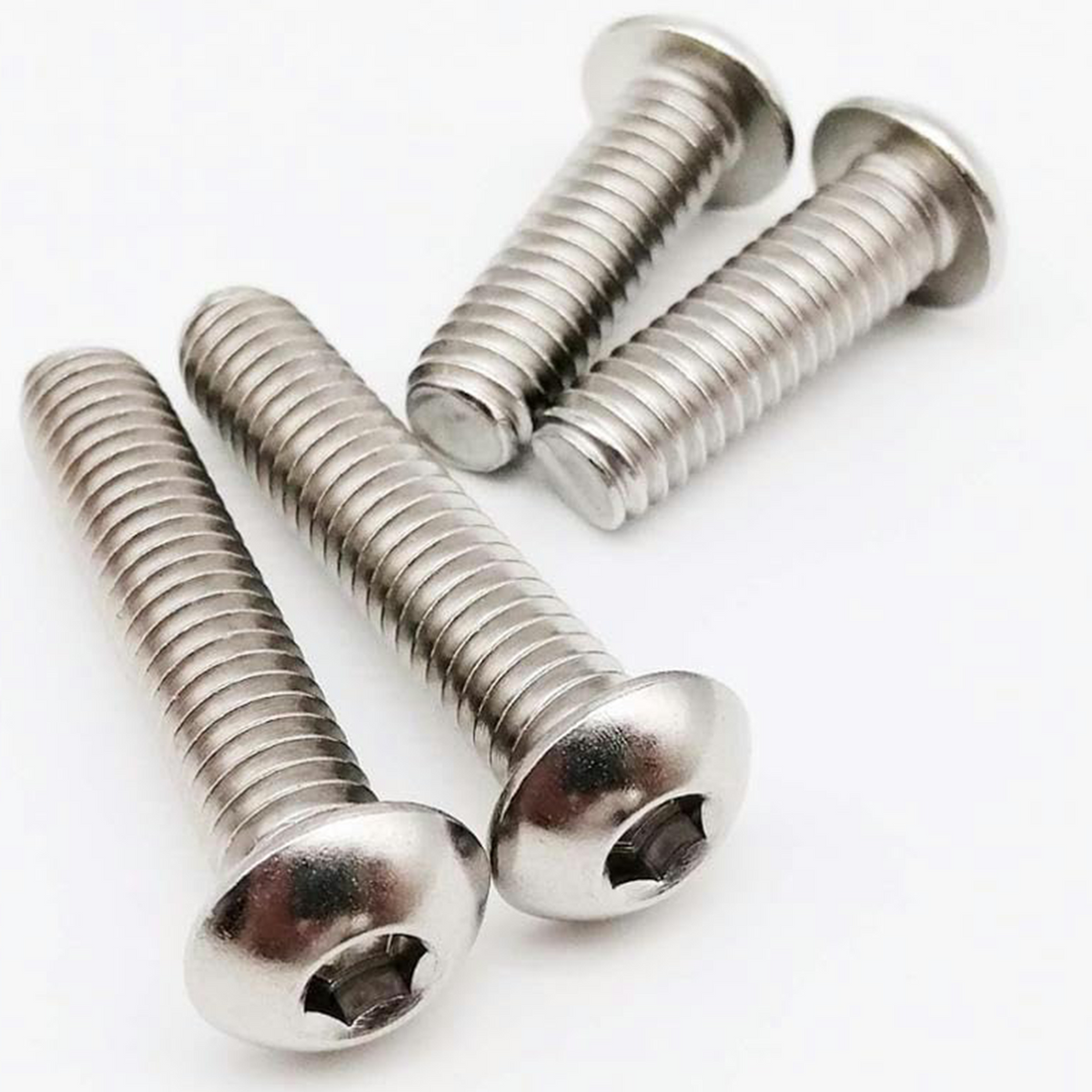 Four A2 stainless steel button head bolts with hex socket heads and fully threaded shanks, close-up