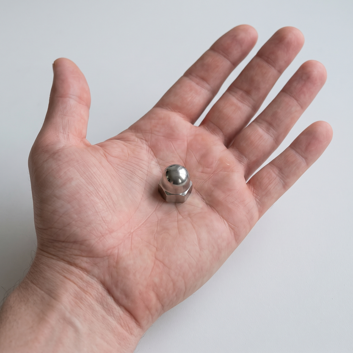 A2 stainless steel M10 dome nut shown in an open hand for scale