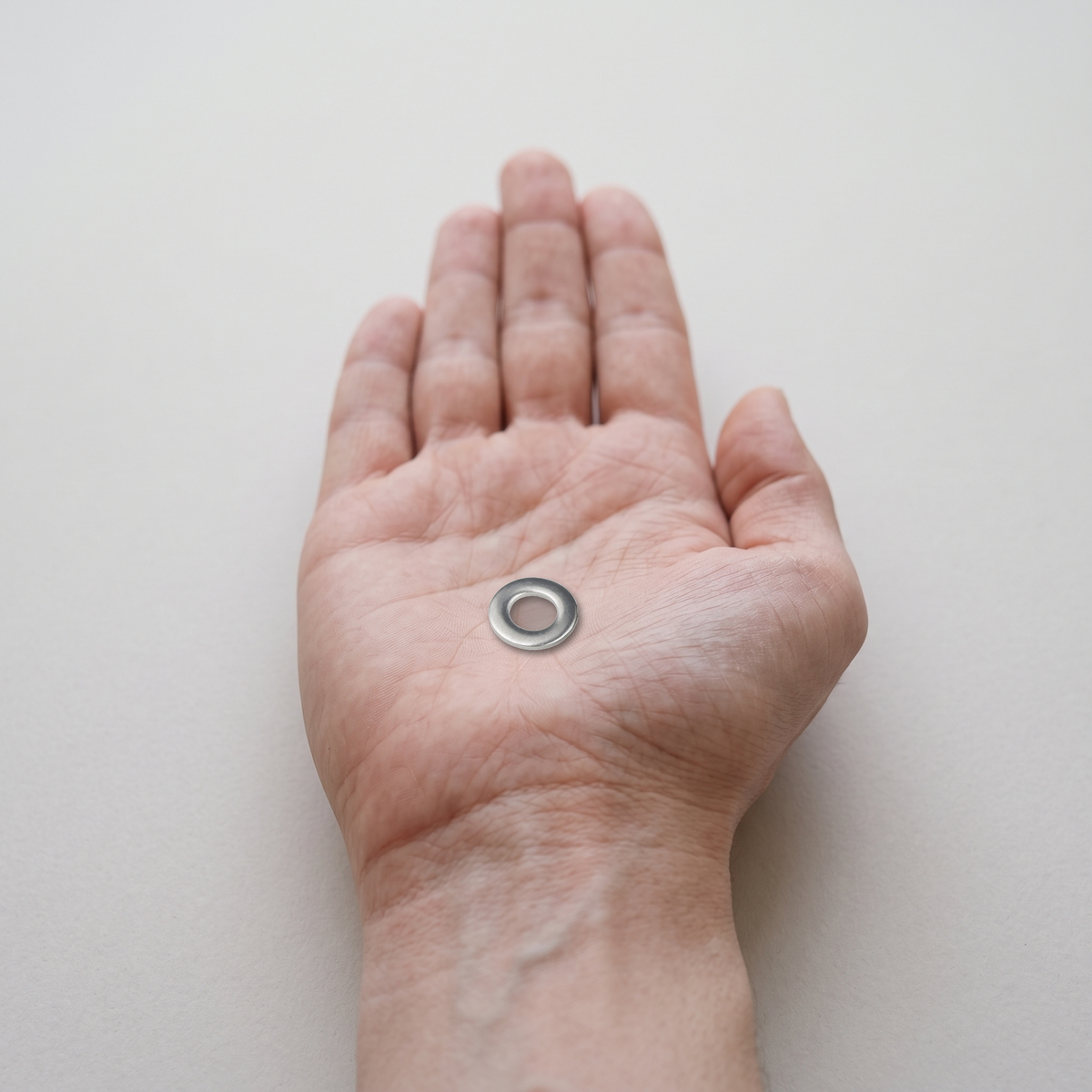 A4 Marine Grade Stainless Steel Flat Washers (DIN 125 / ISO 7089), shown in hand for scale