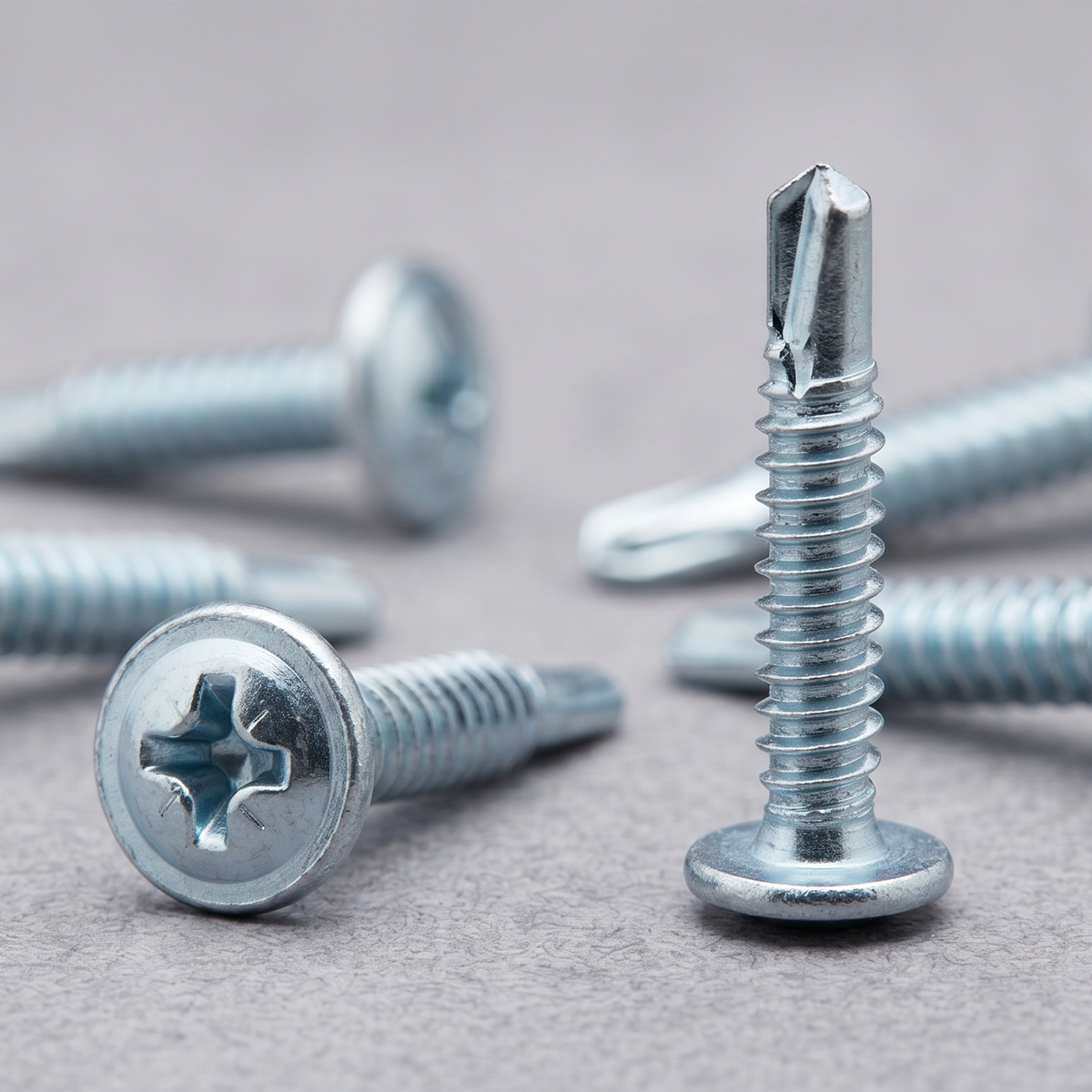Close-up of a bright zinc-plated self-drilling baypole screw with a low-profile wafer head, designed for flush UPVC window installations.