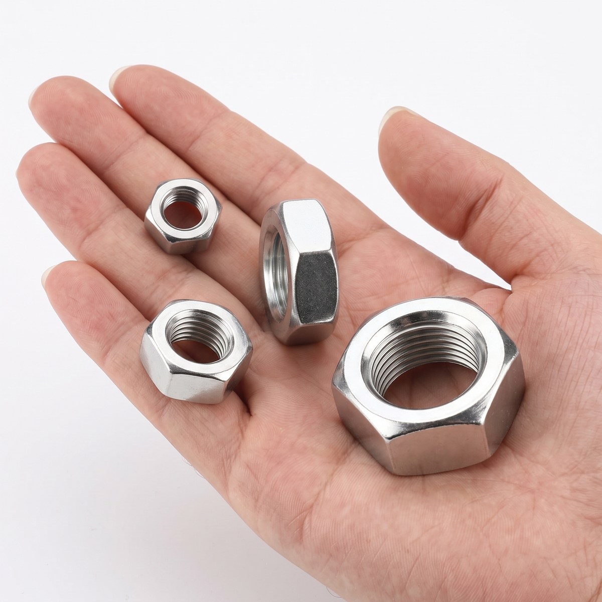 DIYUK Hex Nuts DIN 934, bright zinc-plated BZP finish, four nuts of different sizes shown in hand for scale