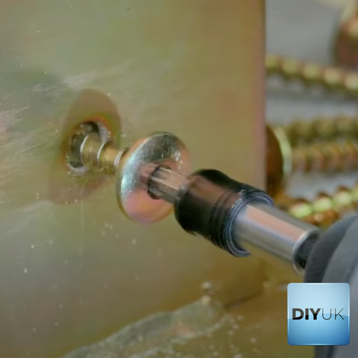 DIYUK close-up of a Torx wafer head screw being driven with a bit holder, with more yellow zinc-plated screws in the background